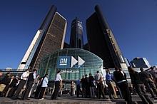 General Motors employees and visitors watch a large video monitor outside the GM World Headquarters.